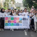 People Walking on a Parade Holding a Banner
