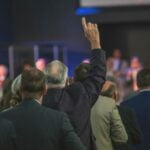 man in black suit jacket standing in front of people