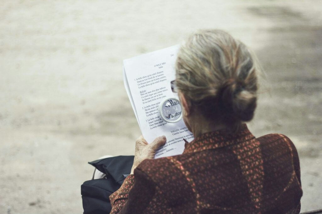 elderly woman in brown top reading paper