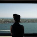 woman wearing off-shoulder shirt standing beside window