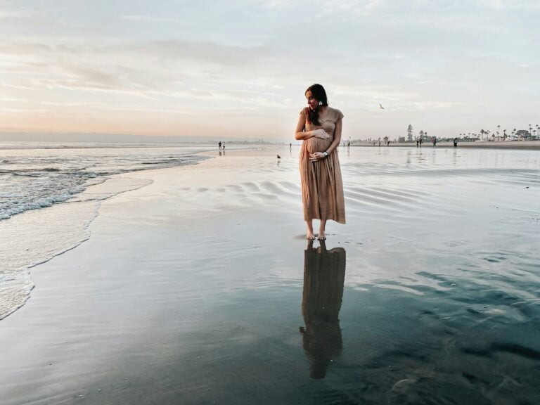 pregnancy: woman in brown dress standing on beach during daytime